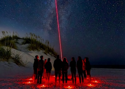 Stephen guiding guests with a star laser on the beach